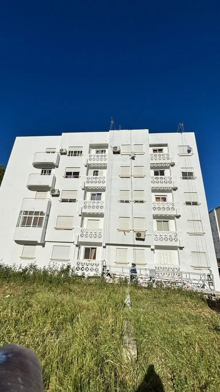 Fachada branca de edifício residencial após pintura exterior.